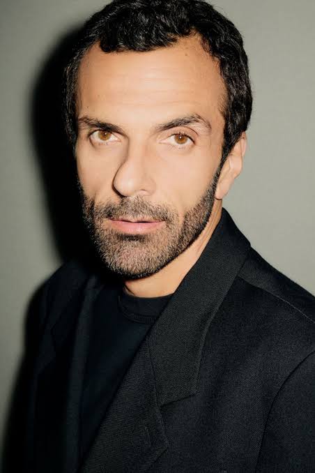 Colour portrait of Cédric Charbit in a black jacket, photographed against a soft grey-green studio wall