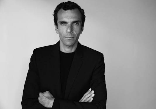 Black and white portrait of Cédric Charbit standing with arms crossed in a dark jacket