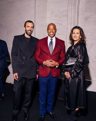 Cédric Charbit standing at the left of a group of three guests at an evening reception in a marble-walled hall