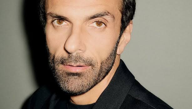 Close editorial study of Cédric Charbit's face in colour, lit against a soft green-grey backdrop