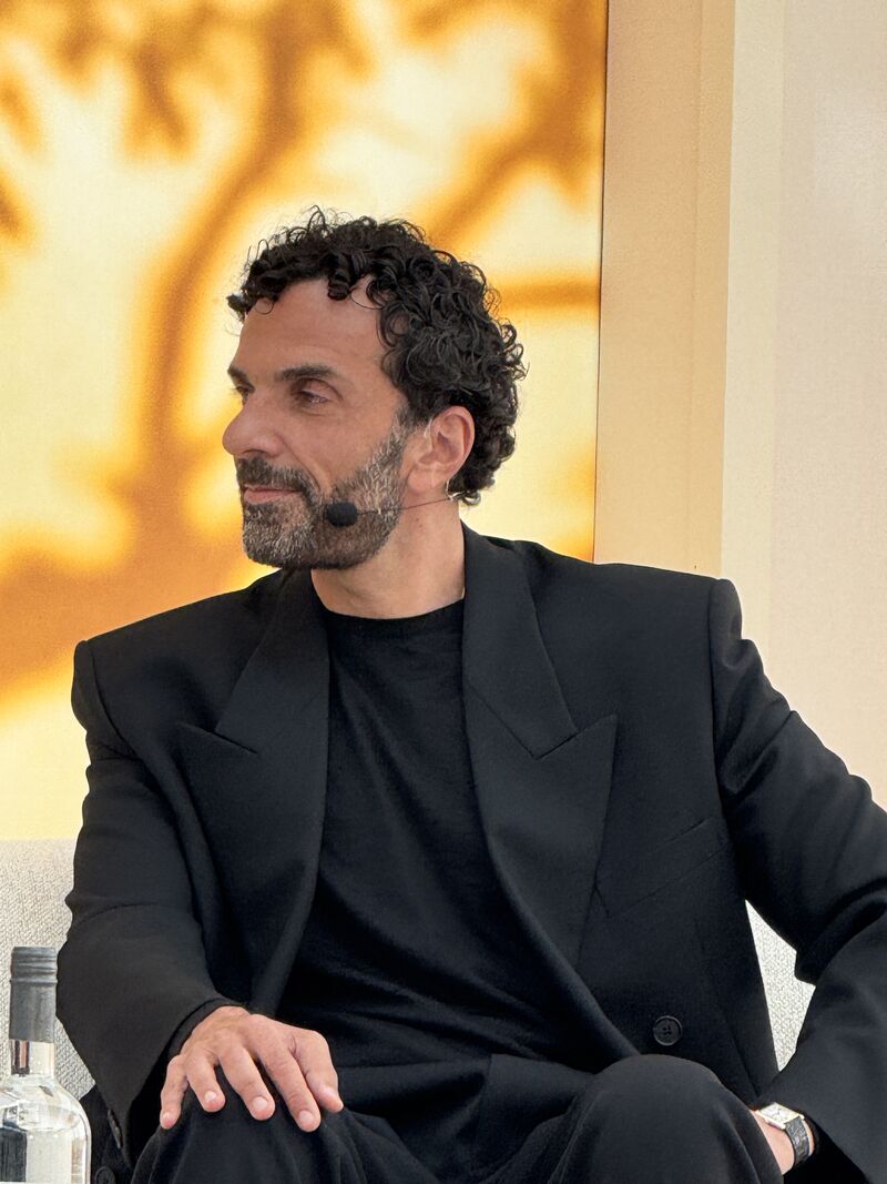 Cédric Charbit seated in a black suit wearing a headset microphone during an on-stage conversation