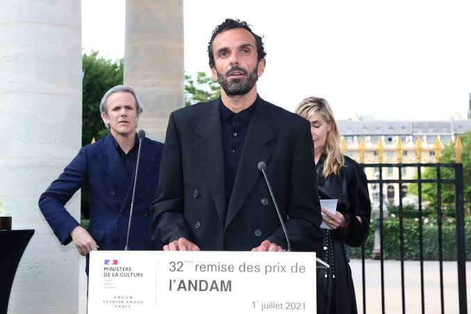 Cédric Charbit speaking at a lectern marked with the 32nd ANDAM prize ceremony, Paris, 1 July 2021, with two guests standing behind him