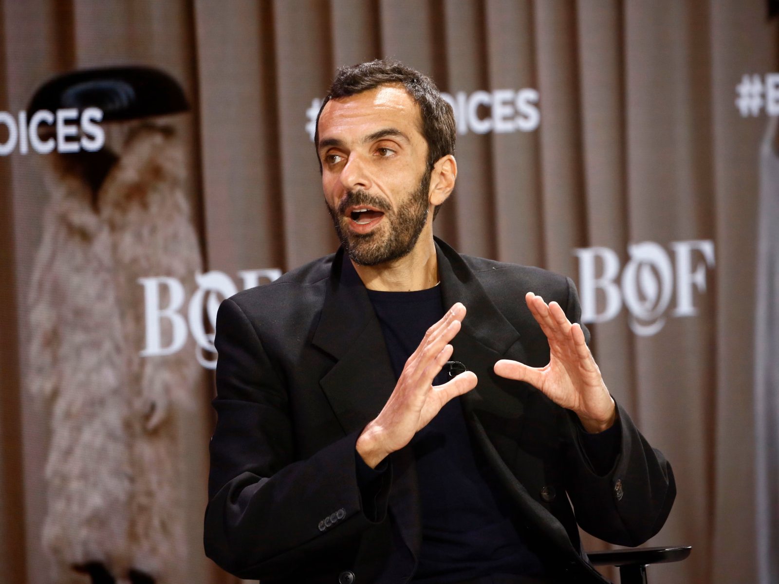 Cédric Charbit speaking and gesturing during a Business of Fashion conference session