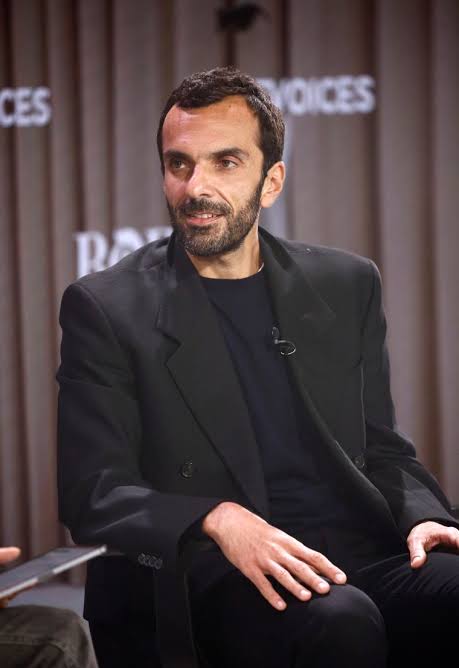 Cédric Charbit seated during a panel discussion in front of a conference backdrop